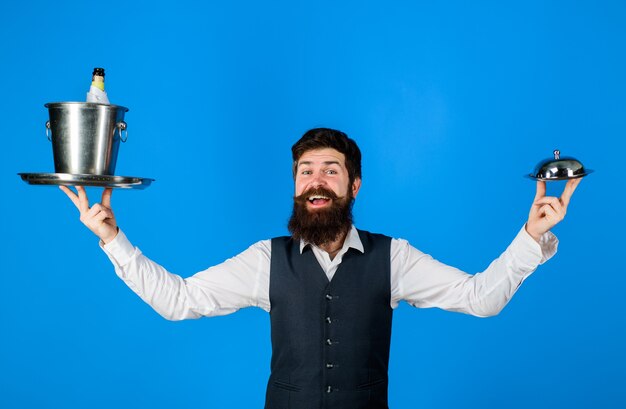 Serveur professionnel dans un restaurant uniforme servant un beau serveur avec plateau de service et refroidisseur à vin