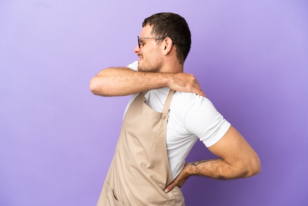 Photo serveur de restaurant brésilien sur fond violet isolé souffrant de douleurs à l'épaule pour avoir fait un effort