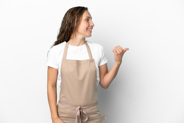 Serveur de restaurant femme caucasienne isolée sur fond blanc pointant vers le côté pour présenter un produit