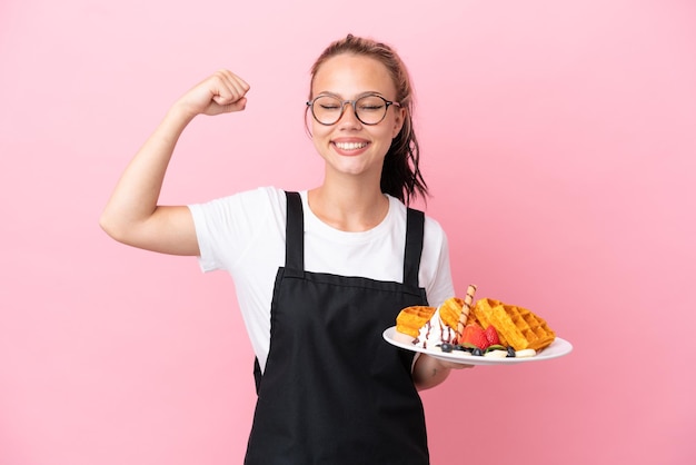 Serveur de restaurant fille russe tenant des gaufres isolées sur fond rose faisant un geste fort