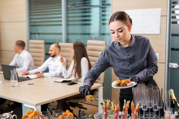 Un serveur de restaurant sert un banquet hors site dans le bureauxA