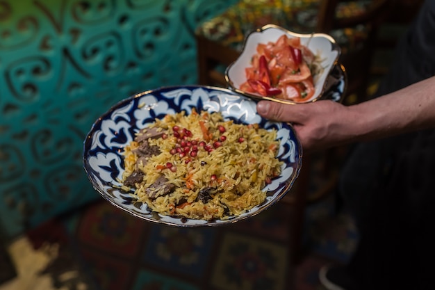 Photo le serveur sert du pilaf à la grenade et aux tomates