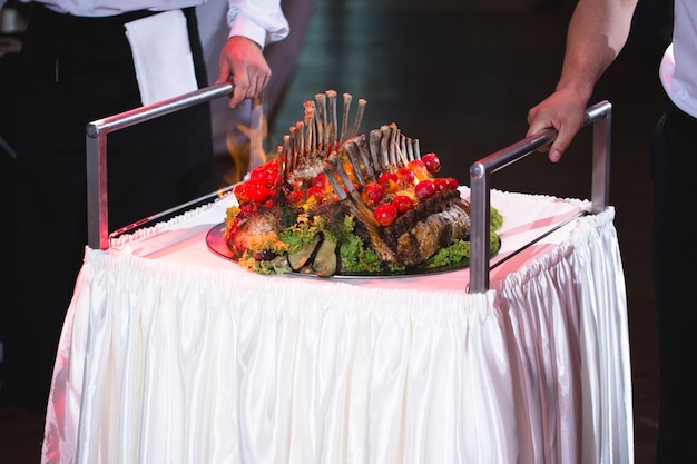 Un serveur sort un carré d'agneau lors d'un banquet de mariage.