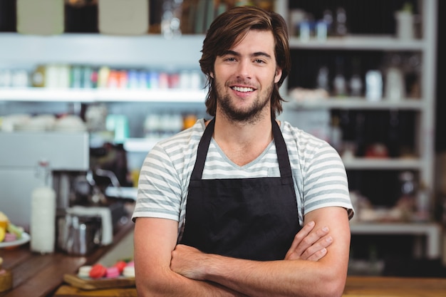 serveur souriant, debout, bras croisé