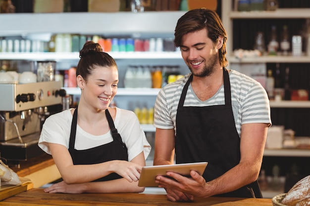 Serveur souriant et serveuse à l'aide de tablette numérique au comptoir