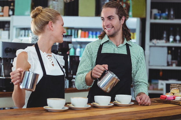 Photo serveur souriant et serveuse faisant une tasse de café au comptoir