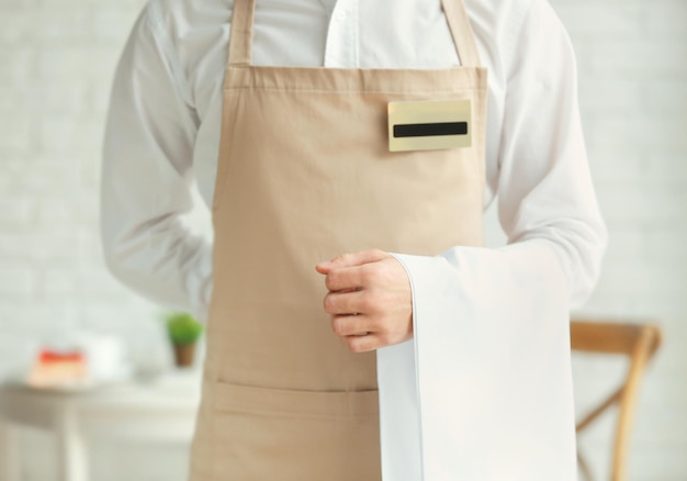 Serveur en tablier beige avec serviette dans un café en gros plan