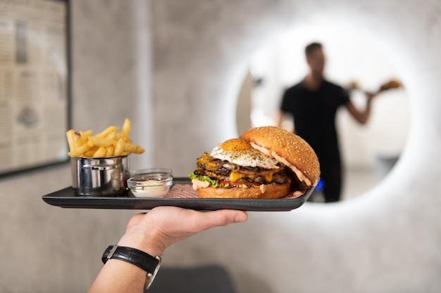 Serveur tenant l'assiette avec hamburger et frites au restaurant