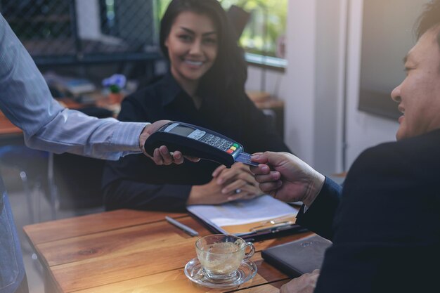 Serveur tenant un lecteur de carte de crédit pour un homme d'affaires payant sa commande à la cafétéria