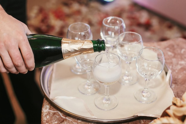 Serveur versant du champagne dans des verres vides à la réception de mariage célébrations de vacances restauration de luxe au restaurant