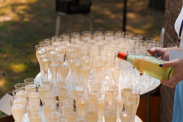 Serveur verse du champagne dans une tasse à vin en plastique jetable