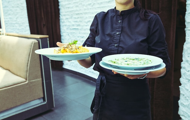 Serveurs portant des assiettes avec plat de viande lors d'un mariage.