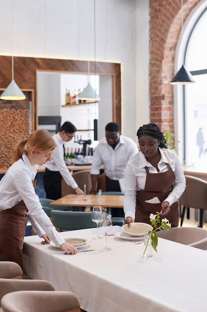 Des serveurs préparent les tables dans un restaurant.