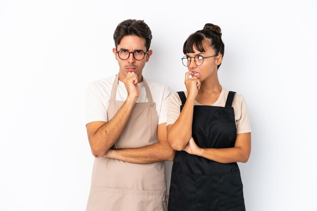 Serveurs de race mixte de restaurant isolés sur fond blanc ayant des doutes tout en levant les yeux