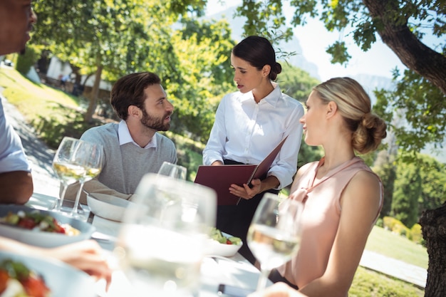 Photo serveuse discutant du menu avec le client dans le restaurant