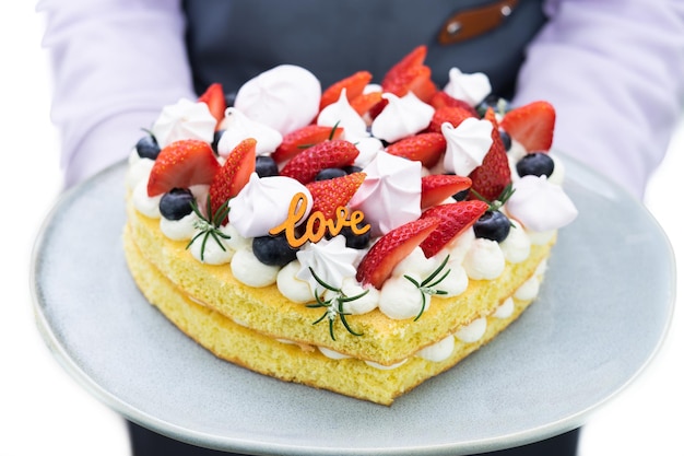 Serveuse femme avec gâteau en forme de coeur décoré de fruits rouges et de meringue Fond blanc Espace copie Saint Valentin