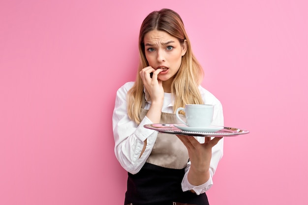 serveuse femme tenant plateau avec tasse sur fond rose isolé stressé et inquiet.