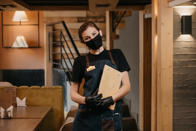 Serveuse en gants médicaux jetables noirs porte un masque médical