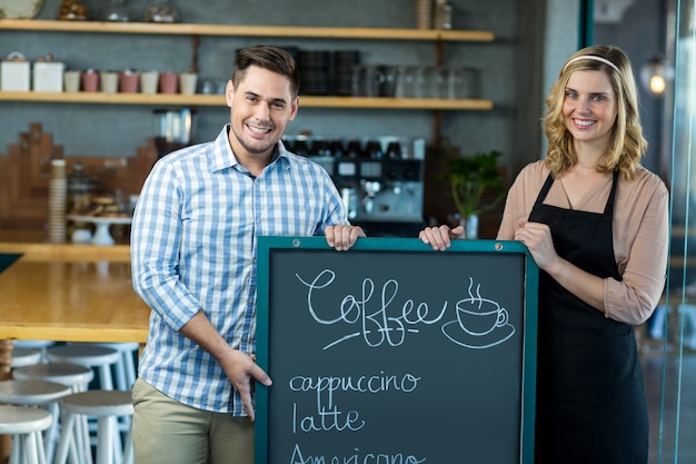 Serveuse et homme debout avec tableau de menu au café