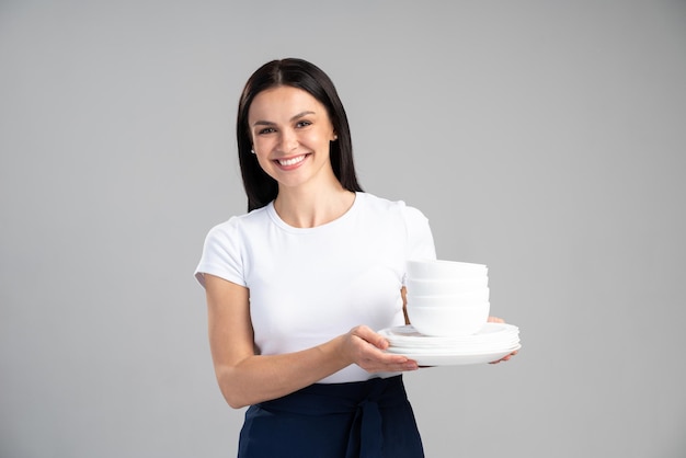 Serveuse, livreuse ou femme de ménage en chemise blanche tenant une assiette blanche vide à ses mains isolées sur fond gris