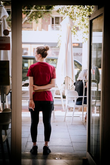 Serveuse à la porte du restaurant regardant la terrasse vide de personnes