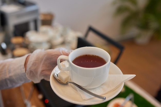 Serveuse près de table avec vaisselle et différentes délicieuses collations pendant la pause-café gros plan