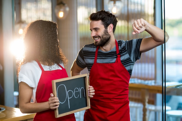 Serveuse et serveur debout avec panneau ouvert au café