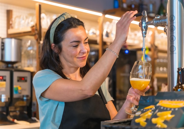 Serveuse souriante brassant une bière blonde dans un robinet les restrictions covid sont levées et l'utilisation obligatoire des masques faciaux est supprimée