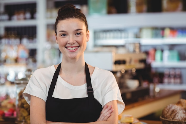 serveuse souriante debout avec les bras croisés