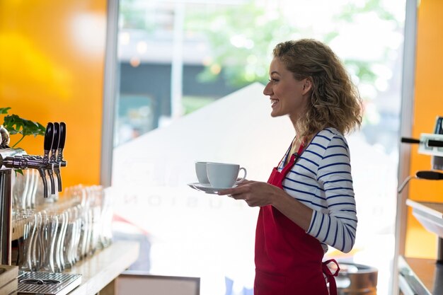 serveuse souriante debout avec une tasse de café