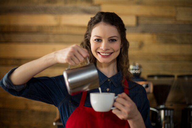 Serveuse souriante faisant une tasse de café