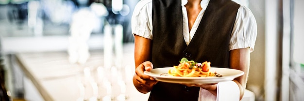 Photo serveuse tenant une assiette de repas dans un restaurant