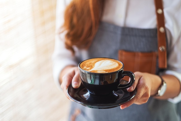 Une serveuse tenant et servant une tasse de café chaud au café