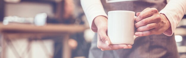 La serveuse tenant une tasse blanche