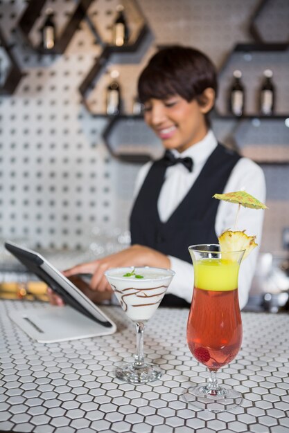 Serveuse, utilisation, tablette numérique, à, verre cocktail, dans, bar, compteur