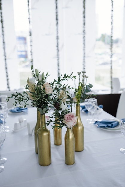 Servi pour la table de banquet de mariage en bleu blanc. Décoration de mariage. Serviette bleue avec fleur sur une plaque blanche. Les bouteilles d'or sont des vases à fleurs.