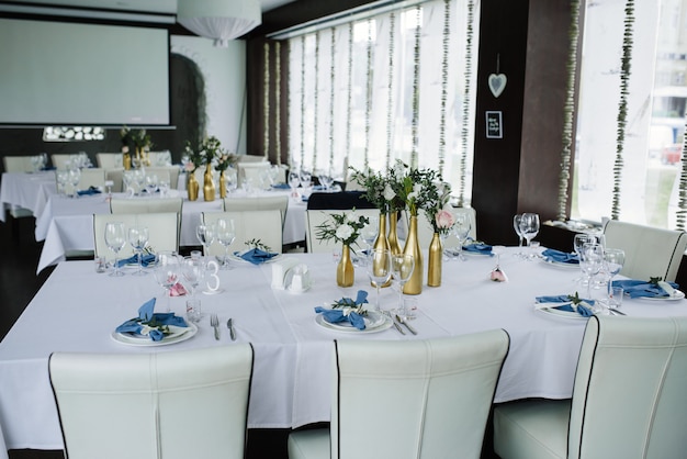 Servi pour la table de banquet de mariage en bleu blanc. Décoration de mariage. Serviette bleue avec fleur sur une plaque blanche. Les bouteilles d'or sont des vases à fleurs.