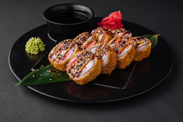 Photo servi des sushis chauds au gingembre et au wasabi sur une plaque en pierre noire