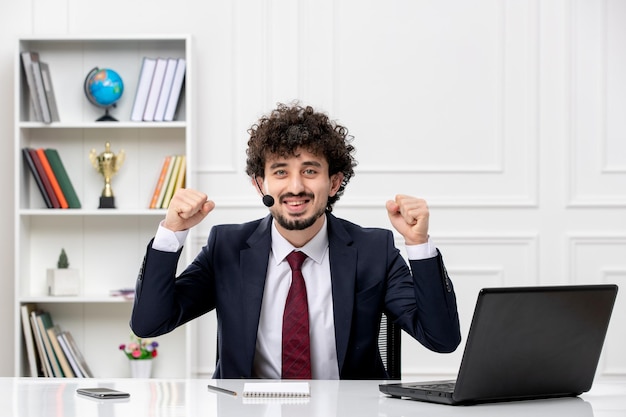 Service client beau jeune homme en costume de bureau avec ordinateur portable et casque excité pour la victoire