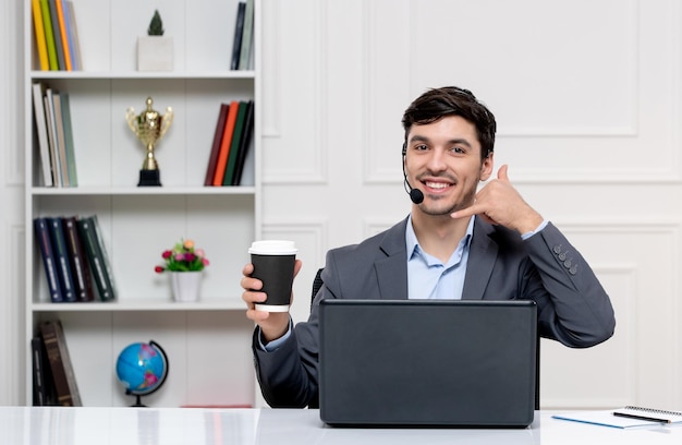 Service client mec mignon en costume gris avec ordinateur et casque faisant un geste d'appel