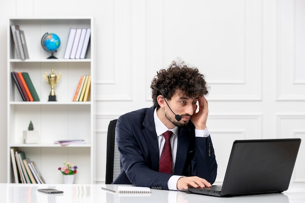 Service à la clientèle beau jeune homme en costume de bureau avec ordinateur portable et casque pensant et travaillant