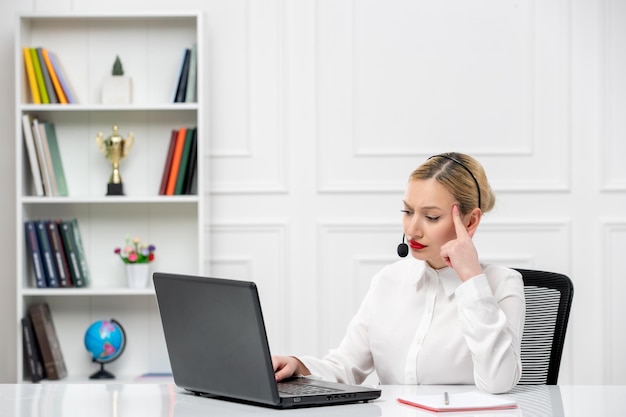 Service à la clientèle jolie fille blonde chemise de bureau avec casque et ordinateur confus touchant les temples