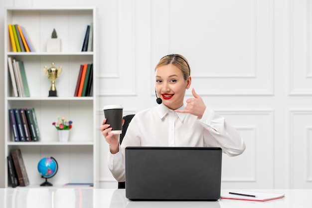 Service à la clientèle jolie fille blonde chemise de bureau avec casque et ordinateur montrant le geste d'appel