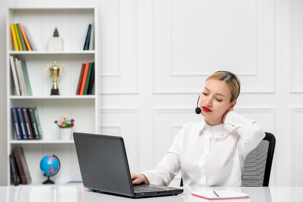 Service à la clientèle jolie fille blonde chemise de bureau avec casque et saisie d'ordinateur