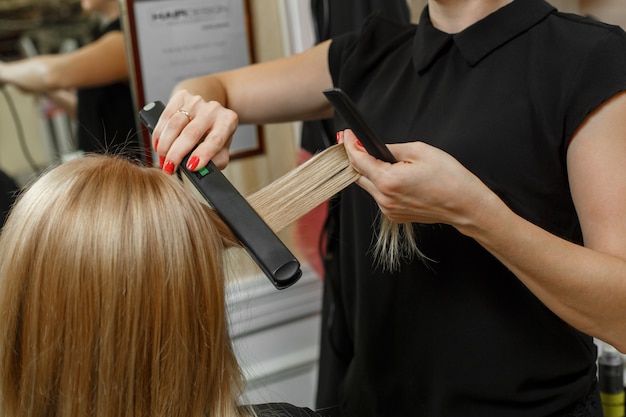 Service coiffure. processus de coupe de cheveux. Processus de coiffure. cheveux mains de maître avec fer à friser professionnel et peigne se bouchent.