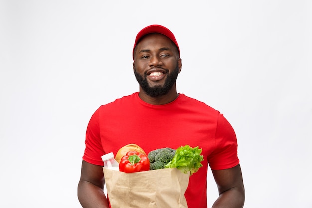 Service de livraison - Bel homme de livraison afro-américain transportant des aliments et des boissons d'épicerie en magasin.