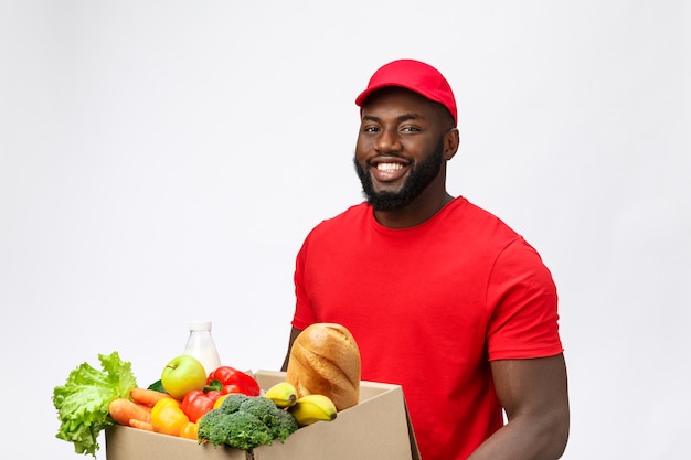 Service de livraison - Bel homme de livraison afro-américain transportant une boîte d'emballage de nourriture d'épicerie et de boisson du magasin.