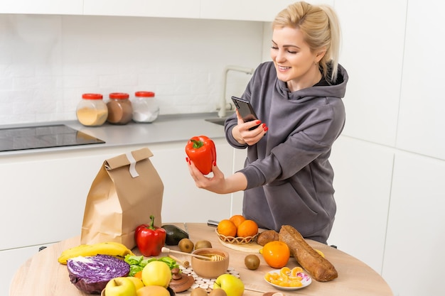 Service de livraison de nourriture - femme tenant un smartphone devant la boîte d'épicerie.