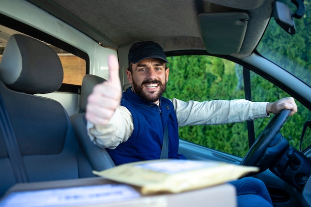 Service de livraison rapide et livreur professionnel dans sa camionnette tenant les pouces vers le haut.