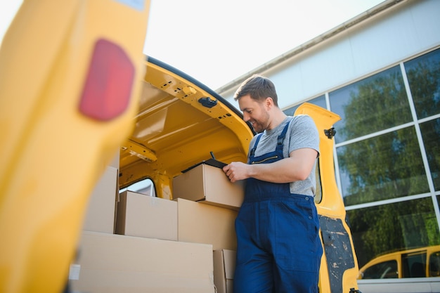 Service de messagerie pour la livraison de marchandises Service express un homme en uniforme livre des boîtes L'employé porte la commande chez le client